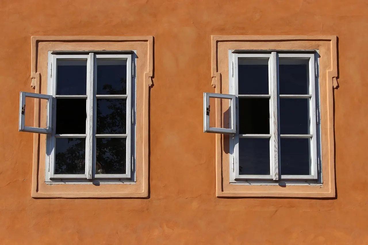 Hvidmalede trævinduer i en varm orange facade